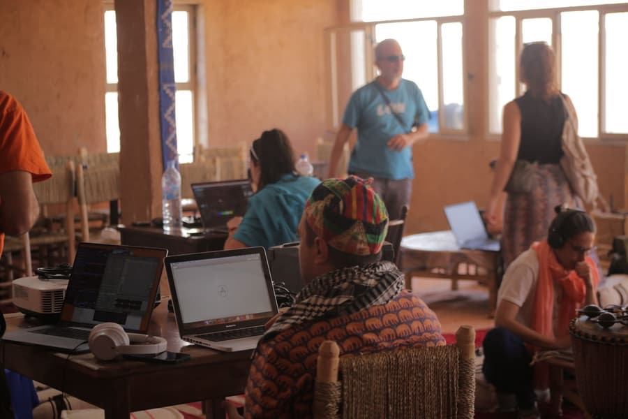 Workshop participants following along on their own laptops in a mud-brick room at LPM 2025